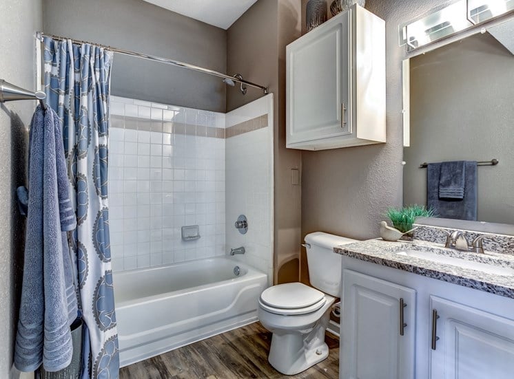 Upgraded model bathroom with tile tub and shower and granite countertops